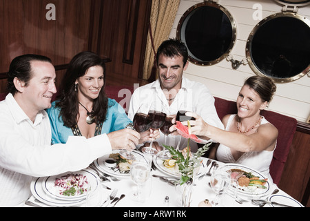 Deux Mid adult couples toasting with wine glasses and smiling Banque D'Images