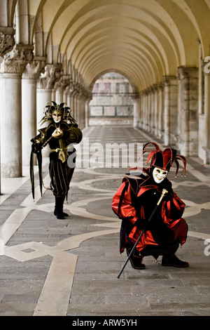 Deux personnes vêtues de costumes et masques de carnaval sous les arches Carnaval de Venise San Marco Square Veneto Italie Banque D'Images