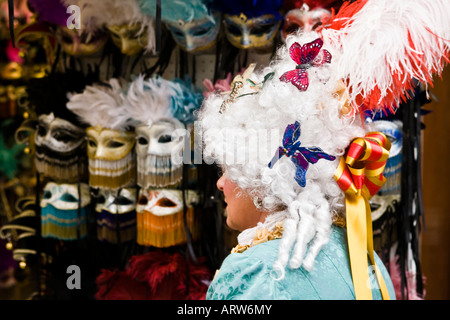 Personne habillé en costume carvial et perruque passe une vitrine masques vente Place San Marco Vénétie Italie Banque D'Images