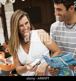 Close-up of a appareil photo numérique et un mid adult man holding un catalogue and smiling Banque D'Images