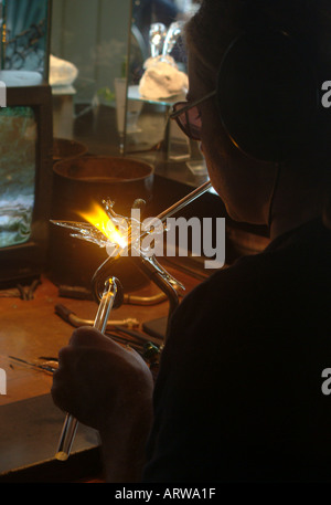 Un sculpteur de verre travaille sur une nouvelle création en faible lumière Banque D'Images