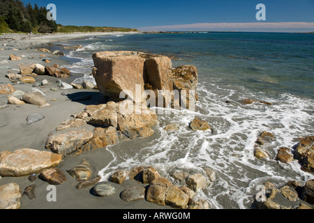 Lap vagues autour des roches sur la magnifique plage de sable du sud de la courbe, l'île de Matinicus, Maine, sous le soleil d'après-midi d'automne. Banque D'Images