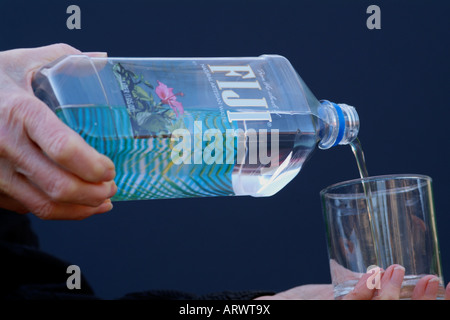 Les Fidji l'eau en bouteille est versé dans un verre. Produit naturel de l'eau cher du Pacifique Îles Fidji Banque D'Images