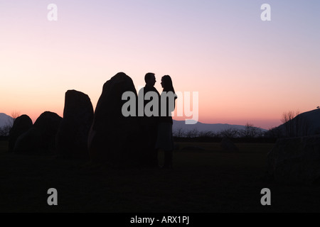 Au coucher du soleil : les amateurs d'un couple sont partiellement découpé sur un coucher de soleil au cercle de pierres de Castlerigg à Keswick, Cumbria, Royaume-Uni Banque D'Images