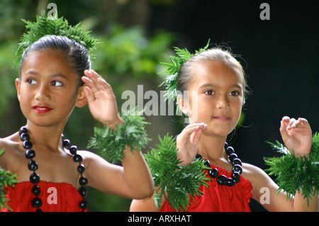 Deux jeunes filles portant des robes rouges et noix de kukui leis danser le Hula. Banque D'Images