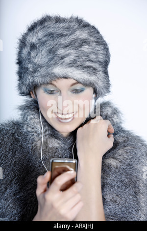 Portrait Portrait d'une belle femme de type russe dans un manteau de fourrure et chapeau portrait Portrait d'une belle femme de type russe dans un manteau de fourrure et de hat en utilisant son lecteur multimédia regardant la vidéo Banque D'Images