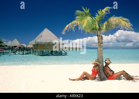 Couple resting sous palmier sur une plage de sable blanc Banque D'Images