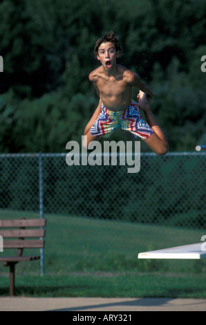 Boy saute d'un plongeoir à un public local piscine Michigan Banque D'Images