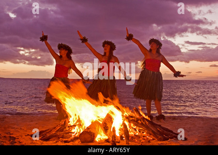 Trois danseurs hula pour exécuter une danse Pele à côté d'un incendie à Makena, Maui. Banque D'Images
