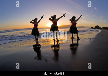 Trois danseurs hula sont découpé par un soleil couchant à Olowalu, Maui. Banque D'Images