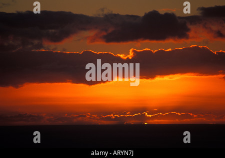 Naufrage du soleil sous l'horizon (océan Pacifique) dramic avec passage des nuages en vu de Maui. Banque D'Images