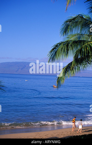 Couple relaxing tôt le matin, promenade le long de la plage de Kaanapali, pirogues et l'île de Lanai dans l'arrière-plan Banque D'Images