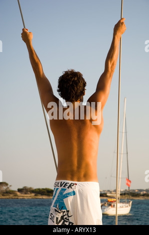 L'homme se balançant de corde à bord d'un bateau à voile Banque D'Images
