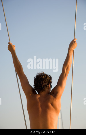 L'homme se balançant de corde à bord d'un bateau à voile Banque D'Images