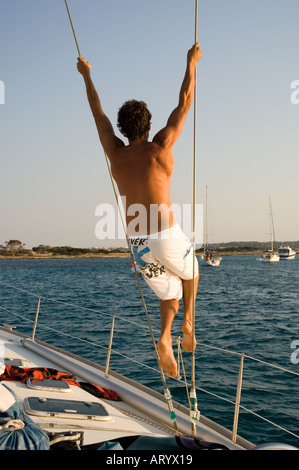 L'homme se balançant de corde à bord d'un bateau à voile Banque D'Images
