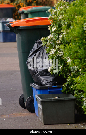 Caisses remplies de matériau de recyclage et wheelie bacs pleins d'ordures domestiques à l'enfouissement et le compostage à l'extérieur de maisons UK Banque D'Images