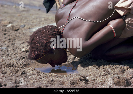 Guerrier Samburu ou moran accroupi à boire de l'eau dans le nord du Kenya Banque D'Images