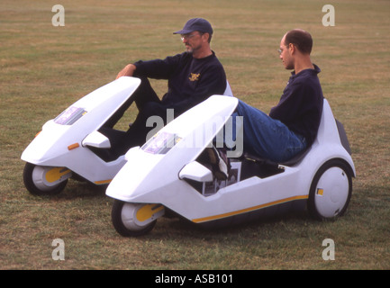 Deux hommes roulant Sinclair C5 scooters Banque D'Images