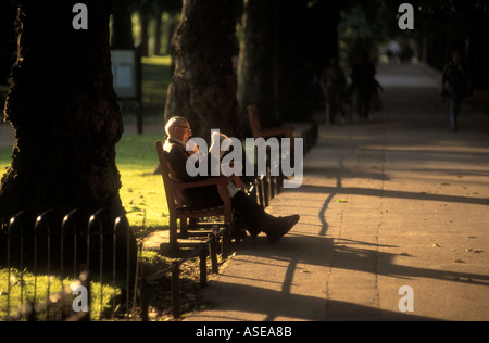 Un vieil homme lit le journal dans le parc par une journée ensoleillée Banque D'Images