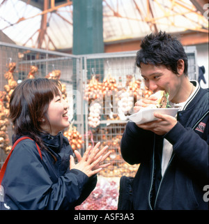 Jeune chinois couple laughing, parler s'amusant de manger des aliments à Borough Market, près de London Bridge à Southwark London UK Sud KATHY DEWITT Banque D'Images