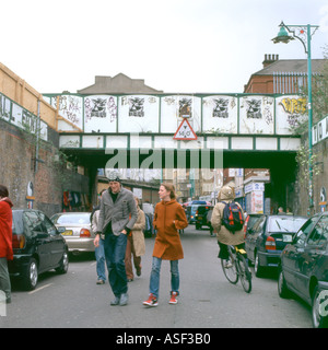 Un jeune couple en train de marcher le long de la rue dans près de le pont de chemin de fer 2004 Brick Lane dans l'Est de Shoreditch London England UK GB Grande-bretagne KATHY DEWITT Banque D'Images