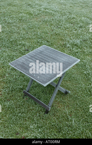 Table de jardin à gauche dans le centre de pelouse à la merci de la nuit froide d'hiver avec forte gelée visible de la table ontop Banque D'Images