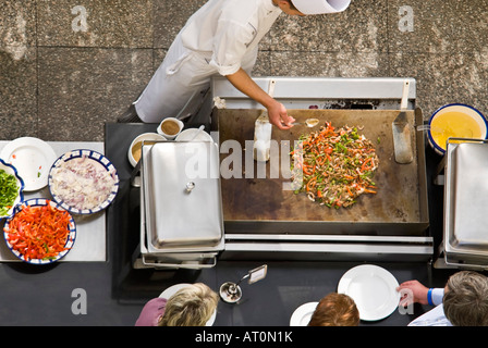 L'antenne horizontale close up d'un chef cuisinier dans la préparation des blancs à l'extérieur un sauté sur plaque chauffante avec les peuples affamés attendent ! Banque D'Images