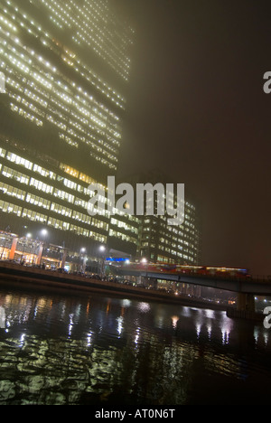 Grand angle vertical d'un train DLR (Docklands Light Railway station Heron Quays laissant à Canary Wharf sur une nuit hivers brumeux Banque D'Images