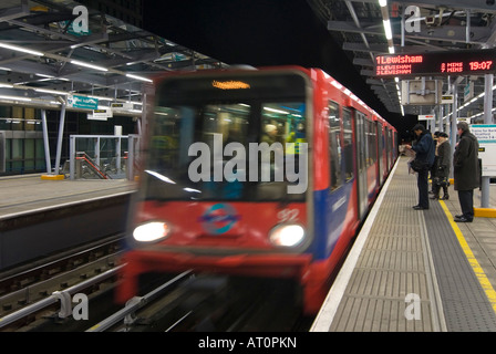 Grand angle horizontal d'un Docklands Light Railway train arrivant en gare de peuplier avec des gens qui attendent sur la plate-forme dans la nuit Banque D'Images