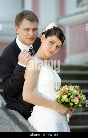 Couple nouvellement marié dans un habit de noces, le marié est attachant un collier autour du cou de sa nouvelle épouse. Banque D'Images