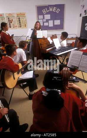 Bande de groupe de musique à l'école enseignant classe groupe multiculturel d'étudiants adolescents jouant divers instruments de musique en classe avec musique livres sur des béquilles Banque D'Images