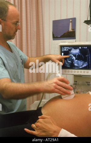 Médecin homme avec sonde sur femme enceinte au cours de test aux ultrasons avec 5-6 mois foetus à l'écran Banque D'Images