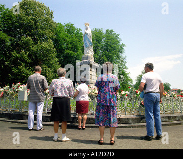 Les touristes réunis autour d'une statue dans les jardins de l'Sanctuaires Notre Dame de Lourdes dans le sud-ouest de la France Banque D'Images