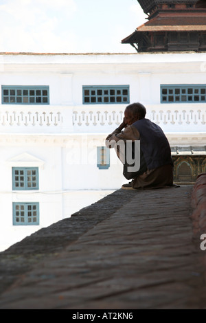 Ancien local homme s'assit sur la marche supérieure d'un temple dédié à Vishnu, le site du patrimoine mondial de Durbar Square à Katmandou, Népal Banque D'Images