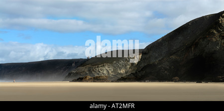 Un couple dans la distance embrasser sur une vaste plage de Cornouailles avec cliffs fluffy clouds and blue sky Banque D'Images