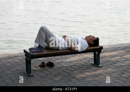 L'homme dort sous un saule, sur les rives du lac TaiYe dans le parc Beihai, Beijing, Chine Banque D'Images