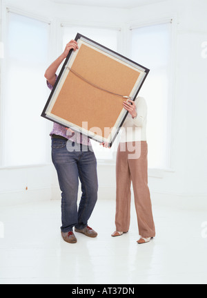 Un homme et une femme s'admirant une photo qu'ils sont sur le point d'accrocher Banque D'Images