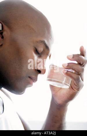 Un homme de race noire tenant un verre d'eau, close-up Banque D'Images