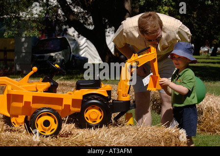 Un père AIDE SON ENFANT JOUER SUR UN JOUET DIGGER À L'INNOCENT FÊTE DU VILLAGE À REGENTS PARK LONDRES 2007 Banque D'Images