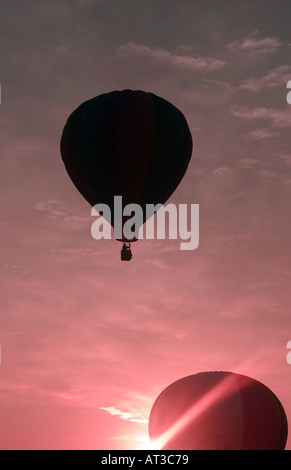 Deux ballons à air chaud qui se profile et le décollage contre soleil levant Banque D'Images