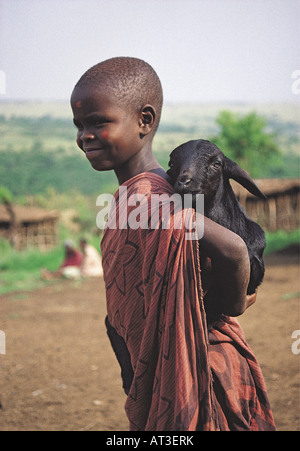 Enfant fille Maasai holding baby chèvre sur son dos au village Masai Masai Mara National Reserve Kenya Afrique de l'Est Banque D'Images