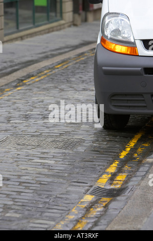 Avant de camionnette blanche avec feux de détresse montrant garé sur les lignes jaunes doubles lumineuses Banque D'Images