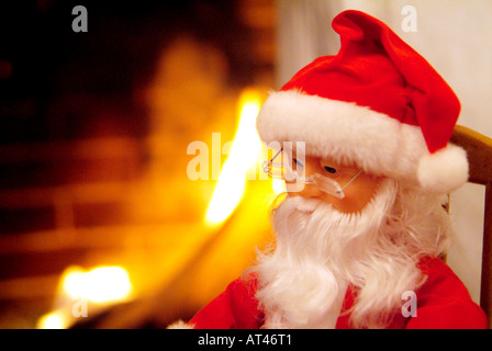 Santa Claus, mannequin assis sur une chaise à bascule à côté de la cheminée Banque D'Images