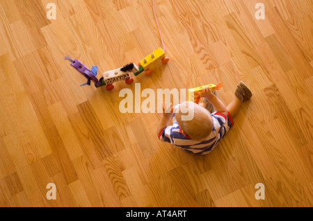 Enfant jouant avec les jouets en bois sur le plancher Banque D'Images