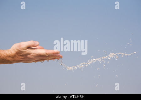 L'eau étant jeté en l'air de mains contre un ciel bleu Banque D'Images