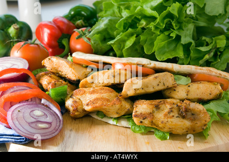 Une douce chaude Chicken shish kebab servi sur un plateau en bois dans un pain pita avec de la salade Banque D'Images