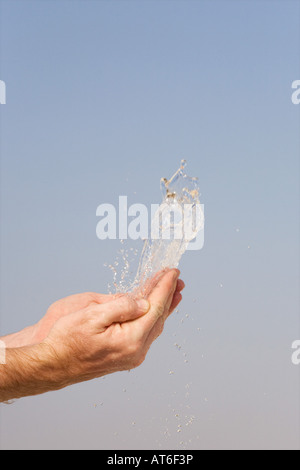 L'eau étant jeté en l'air de mains contre un ciel bleu Banque D'Images