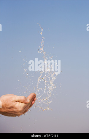 L'eau étant jeté en l'air de mains contre un ciel bleu Banque D'Images