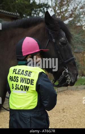 Pony Rider portant veste de sécurité inscrits Veuillez passer lentement l'échelle Little Girl holding son animal Poney Cob Banque D'Images