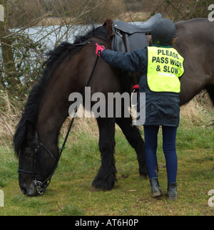 Pony Rider portant veste de sécurité inscrits Veuillez passer lentement l'échelle Little Girl holding son animal Poney Cob Banque D'Images